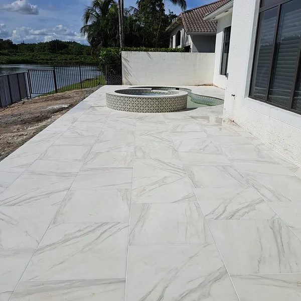 Spacious backyard patio with white porcelain pavers and waterfront view