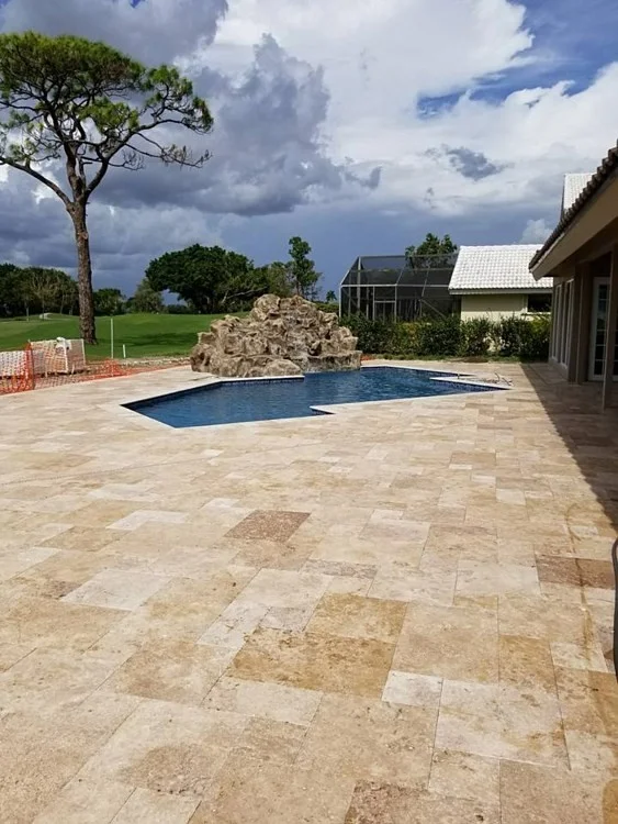 A modern pool with a travertine paver pool deck