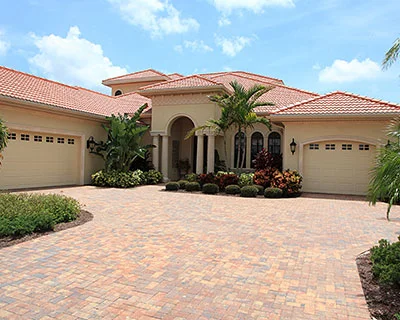 A home with a wide driveway and tropical surroundings