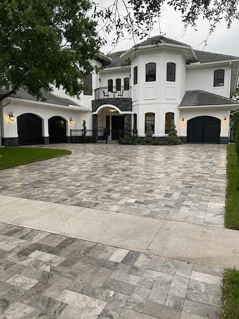 Upscale home with a large, luxurious driveway with light gray pavers