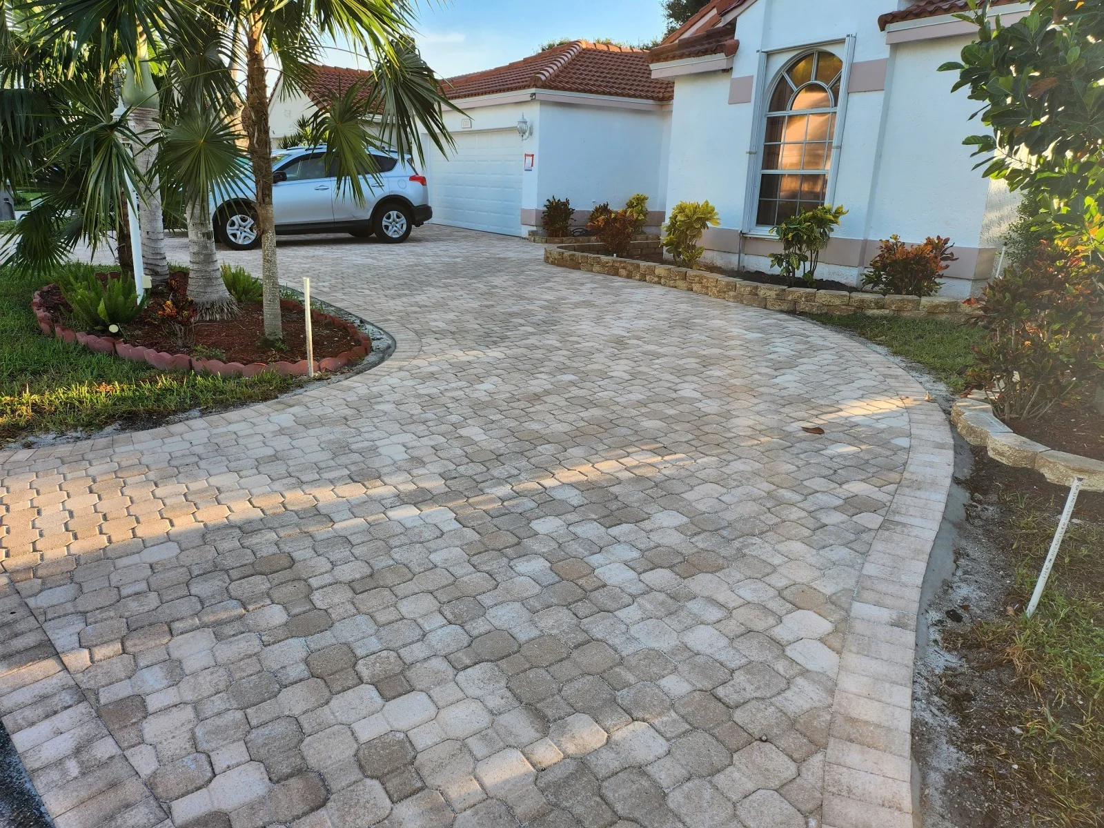 A driveway paver installation leading up to a white house in Palm Beach County, FL