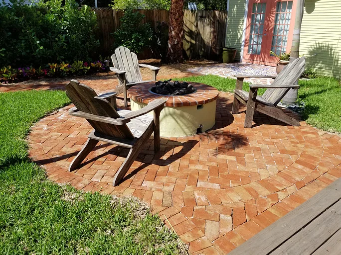 A circular patio installed with clay pavers featuring a built-in fire pit in Palm Beach County, FL