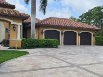 Large house with three garage doors and a wide paver driveway