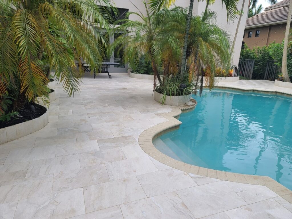 Luxurious marble pavers surround a swimming pool and palm trees