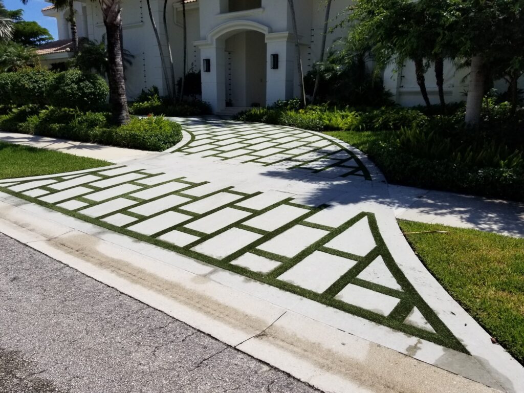 A modern driveway with white concrete pavers and grass joints