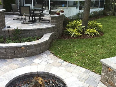A multi-level paver patio with a dining area and fire pit