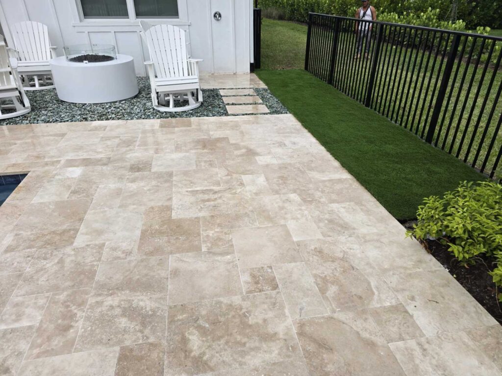 A pool deck next to artificial turf and white chairs