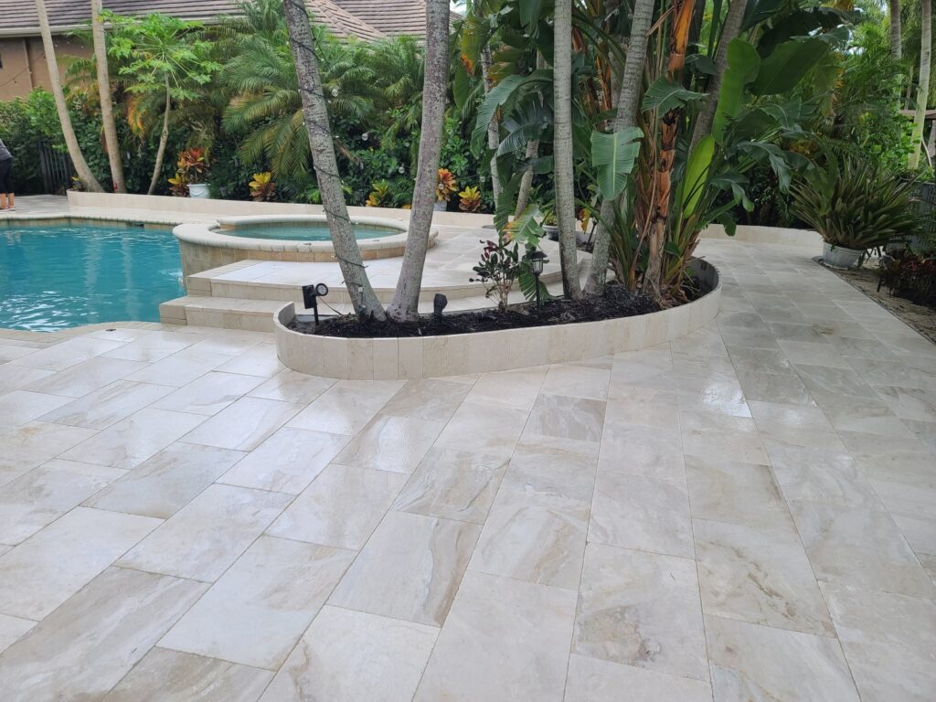 A swimming pool deck with marble pavers and palm trees